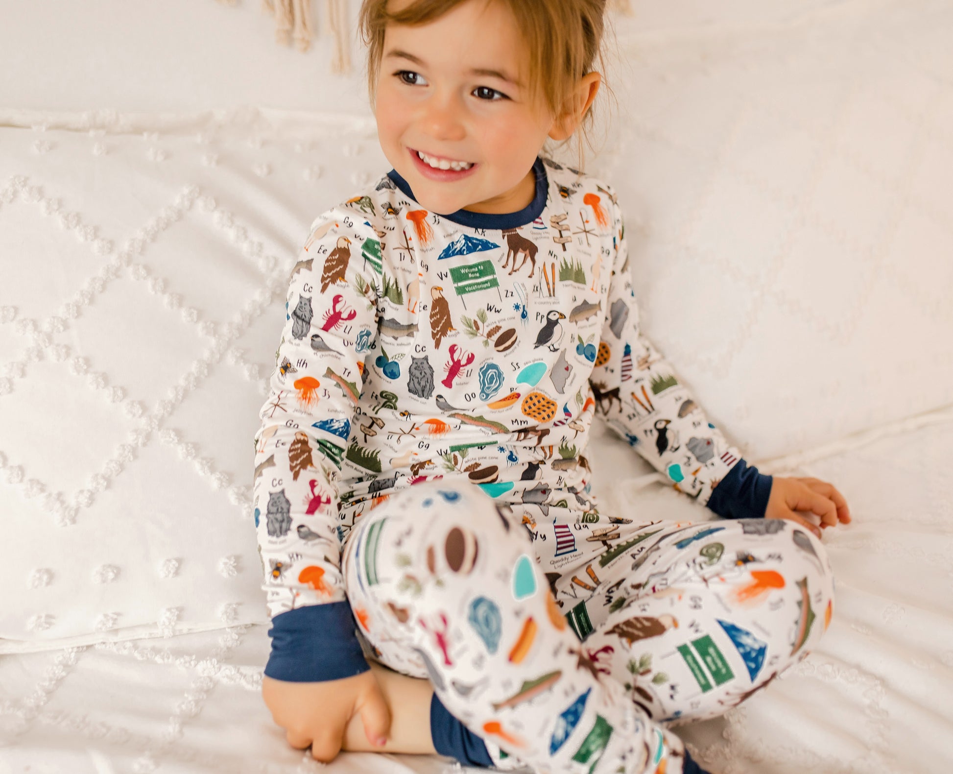 Child wearing a colorful pajama set with all kinds of Maine themes for every letter of the alphabet 