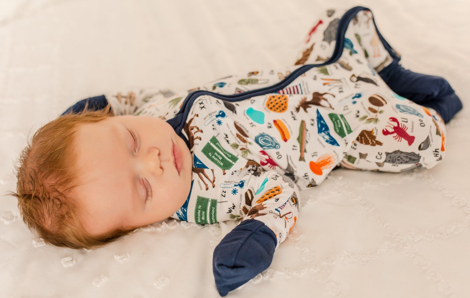 Child wearing a colorful pajama set with all kinds of Maine themes for every letter of the alphabet 
