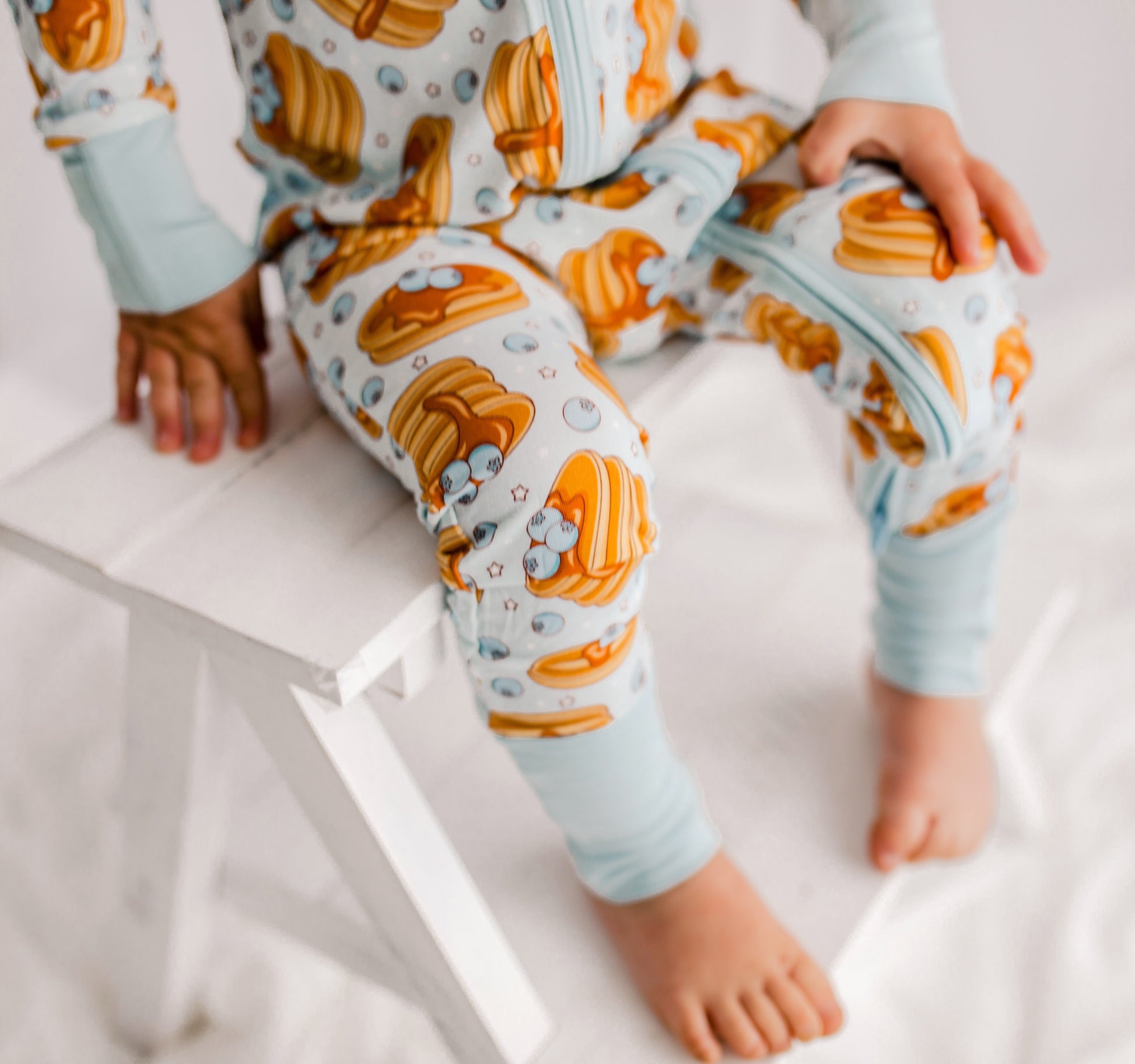 Stacks of pancakes with dripping syrup and maine blueberries on a light blue background with little stars 