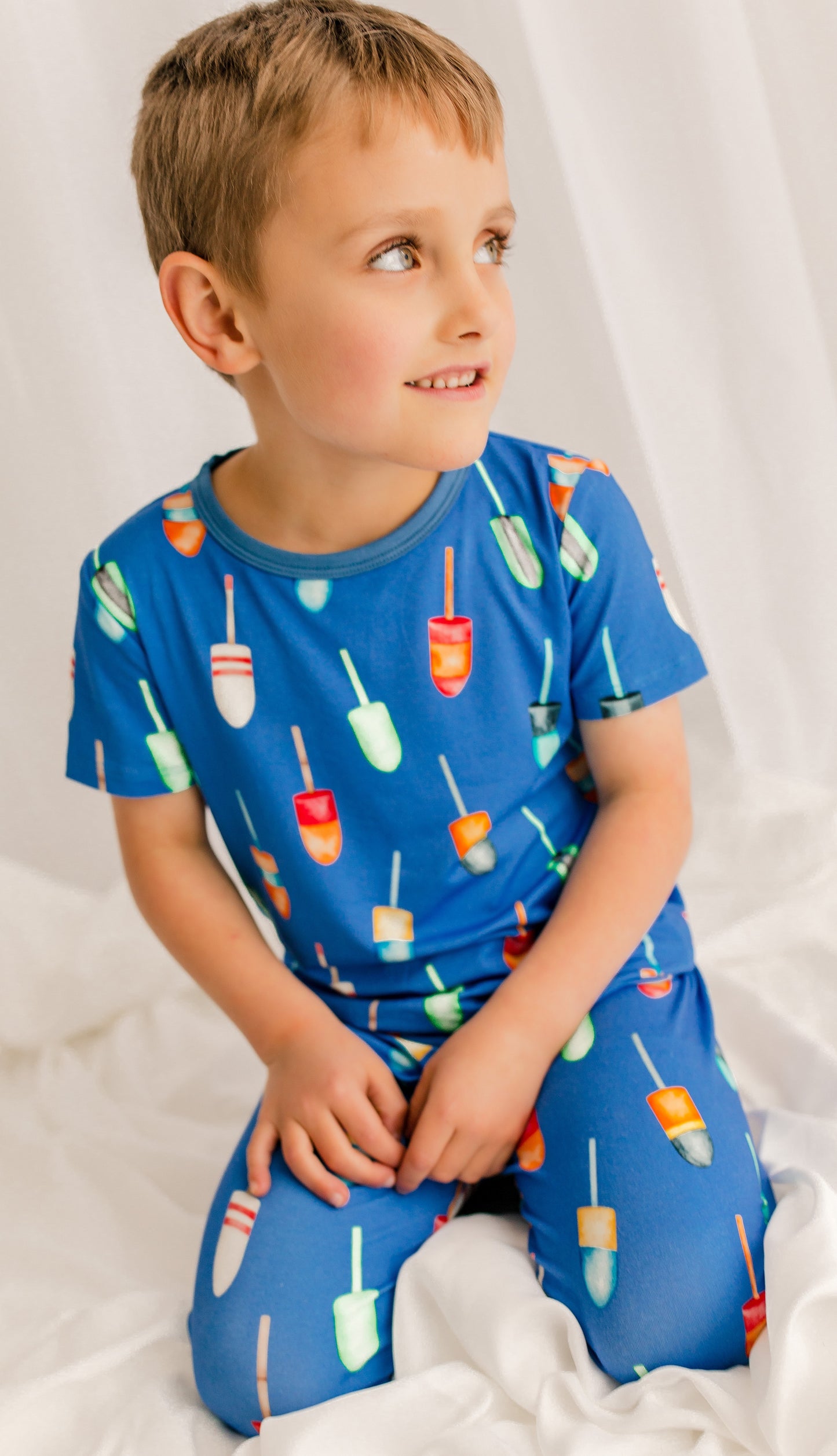 Child wearing a blue pajama set with all different color family buoys 