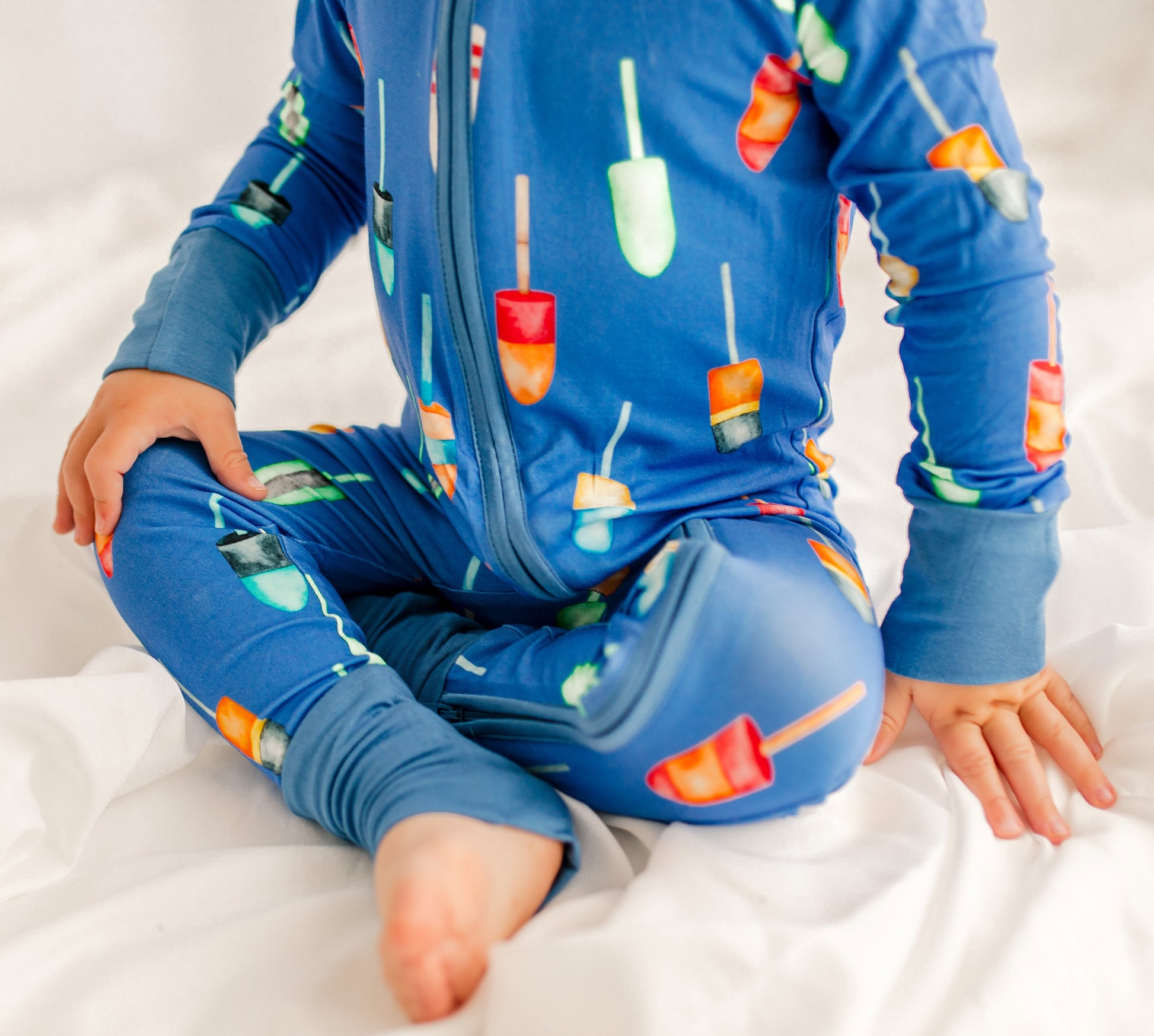 Child wearing a blue onesie with colorful family maine buoys all over 