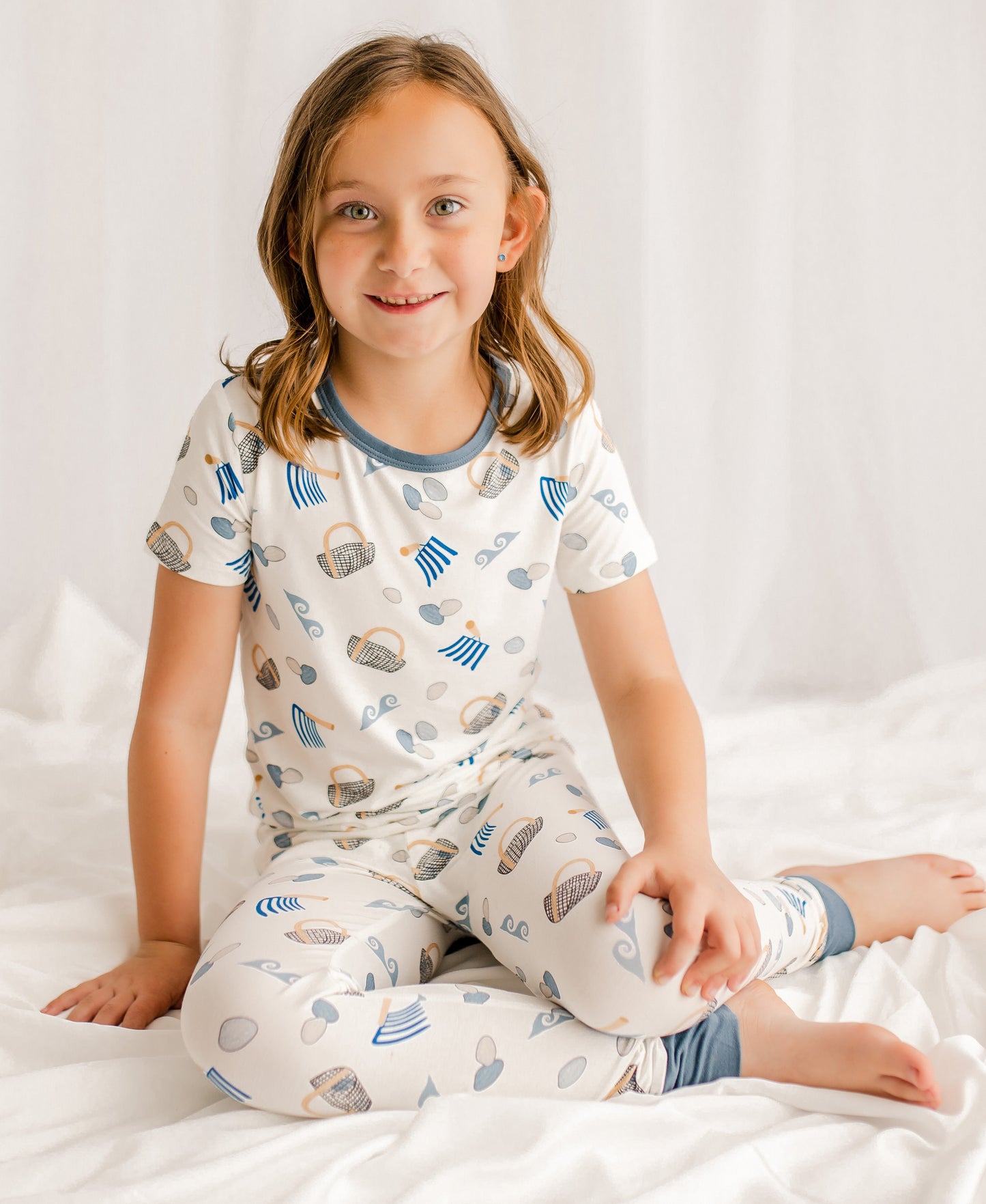 Child wearing a pajama set with clamming patterns on a white background