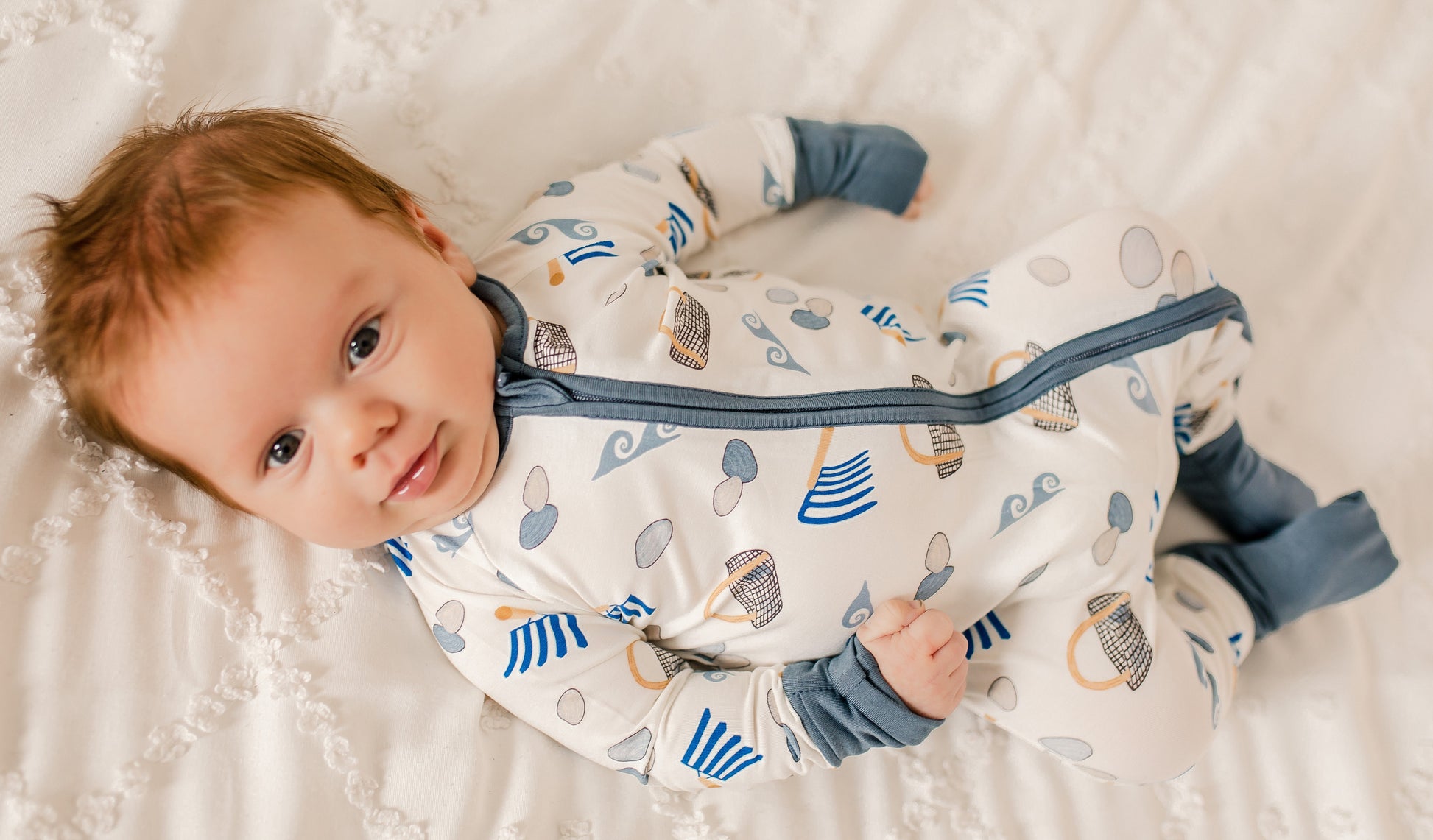 Child wearing white background zippy with gray cuffs with clamming designs all over 