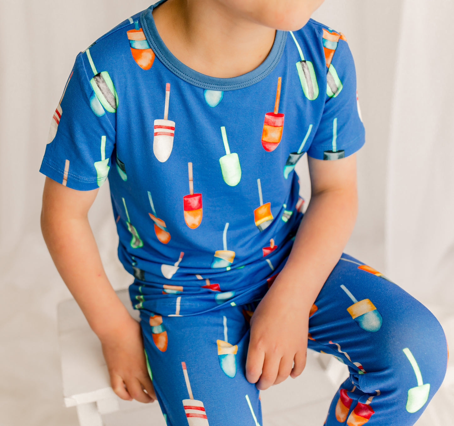 Child wearing a blue pajama set with all kinds of buoys with different patterns and colors 
