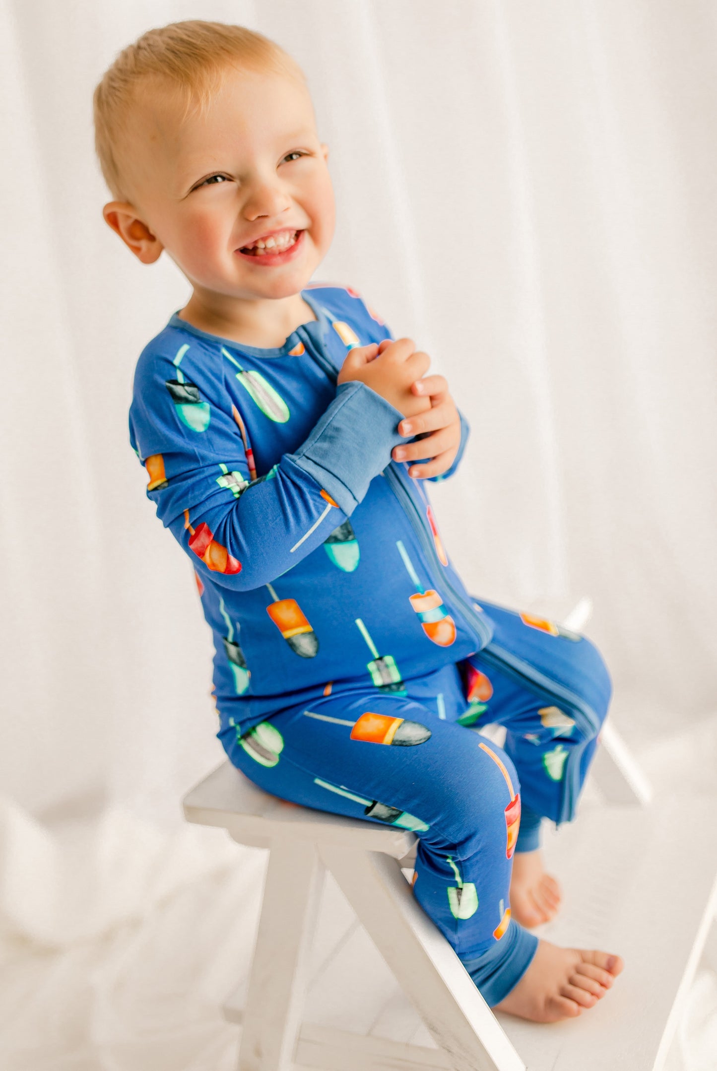 Child wearing blue pajamas with all kinds of buoys in all different colors and patterns 