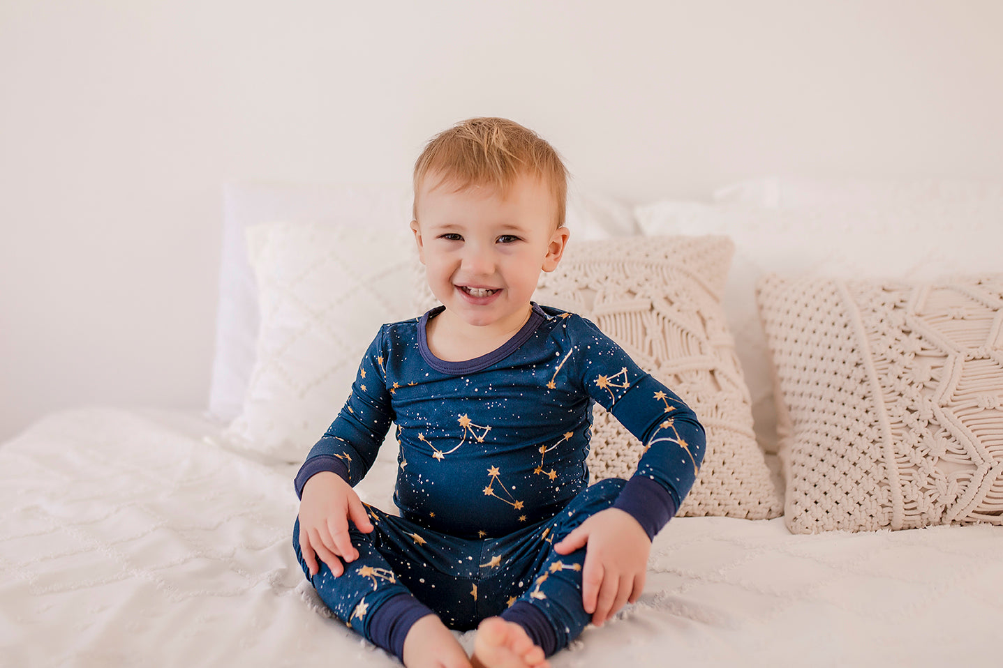 Child wearing a long sleeved dark blue pajama set with the little dipper and big dipper along with the galaxy and stars 