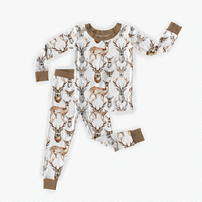 A two-piece pajama set for children with a deer and antler design on a white background and brown accents.