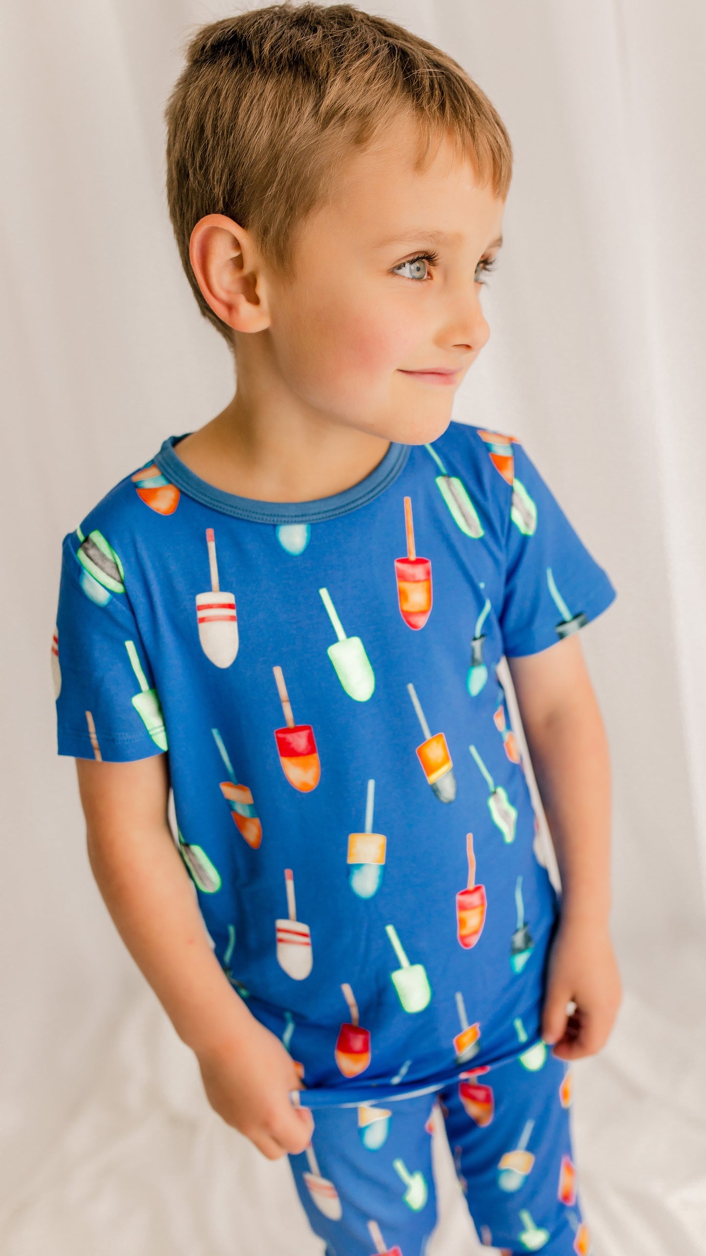 Child wearing a blue pajama set with all different color family buoys 