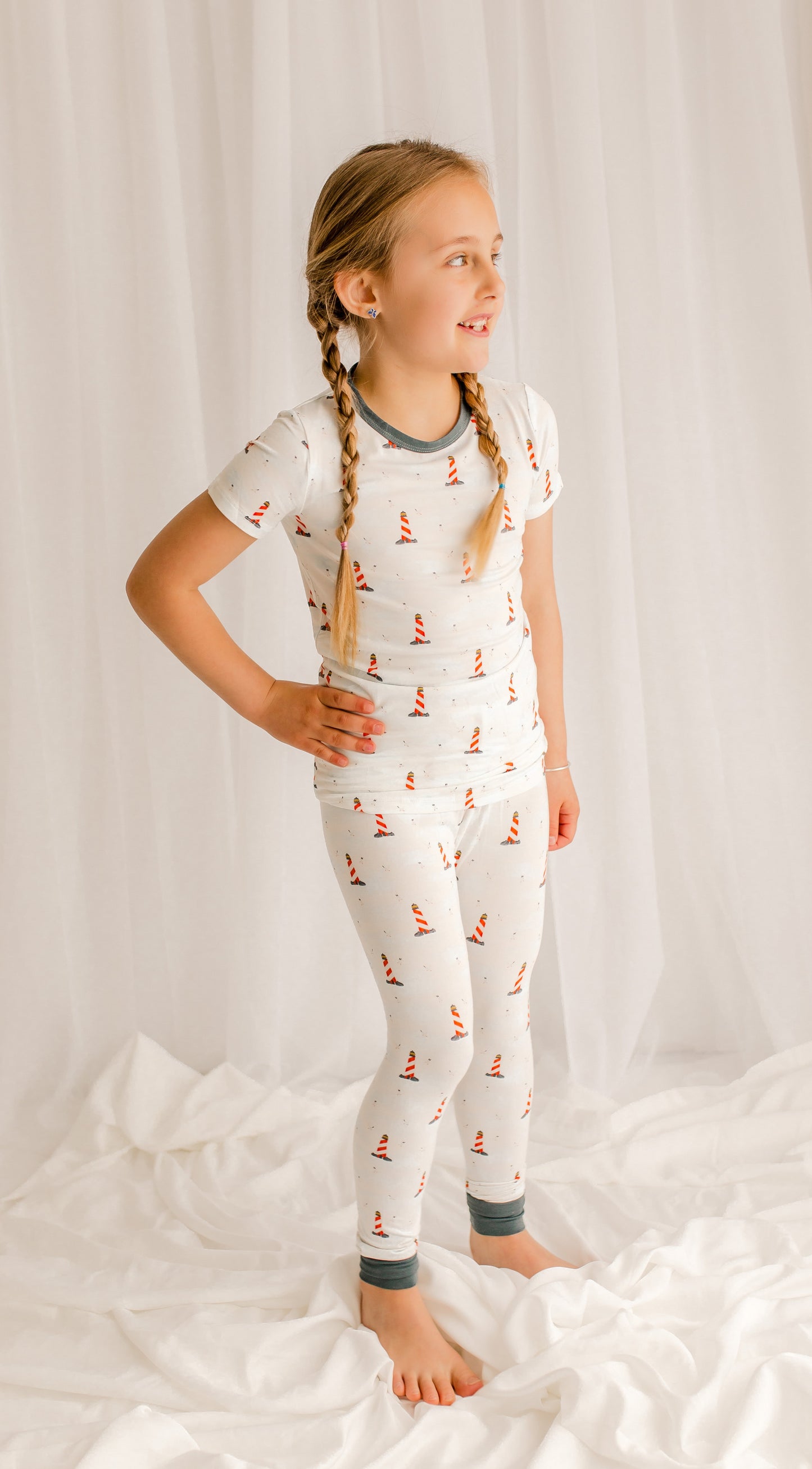 Young girl wearing a white pajama set with a lighthouse pattern 
