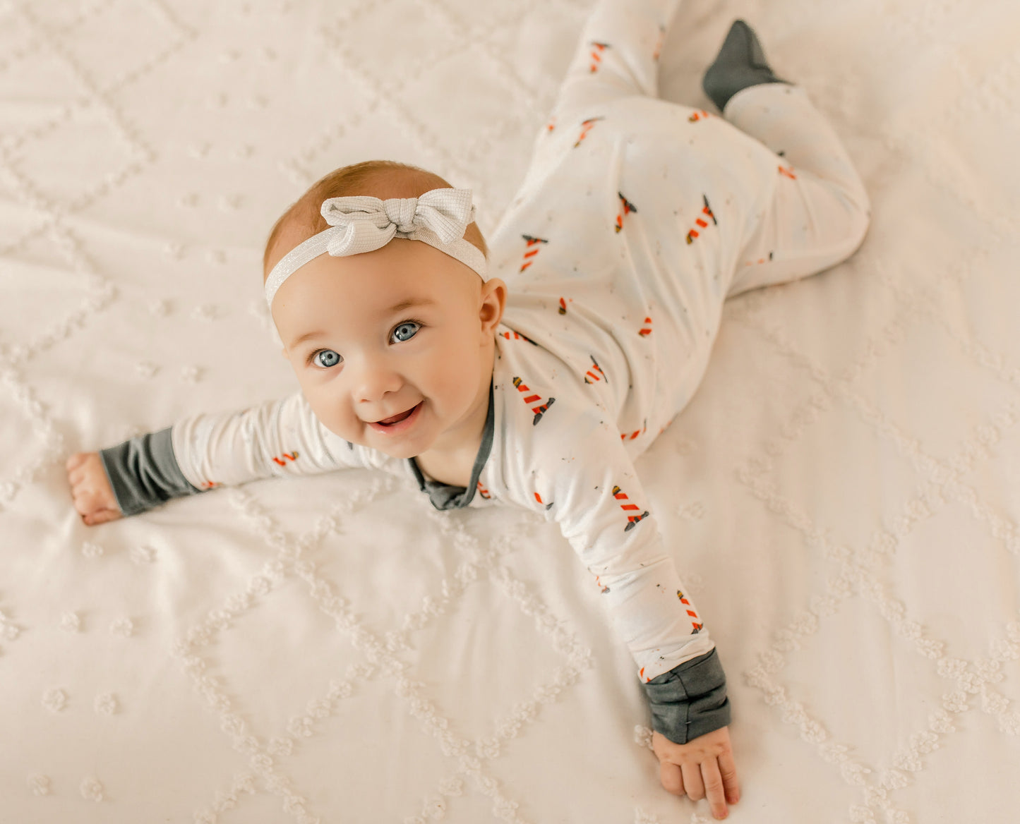 Baby wearing a white one piece with black cuffs and red and white lighthouse  patterns