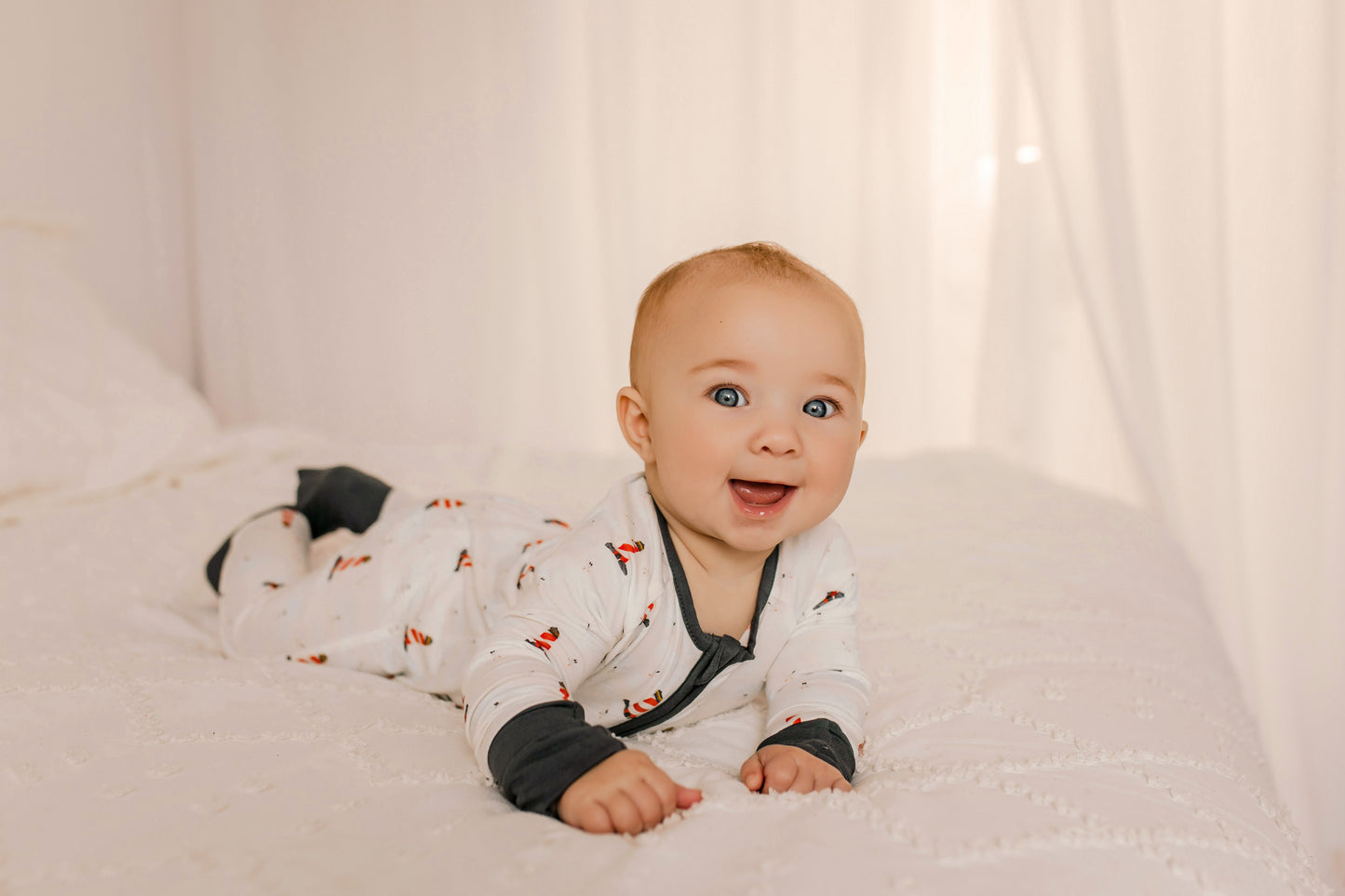 Baby wearing a white one piece with black accents and Maine lighthouses in red and white 