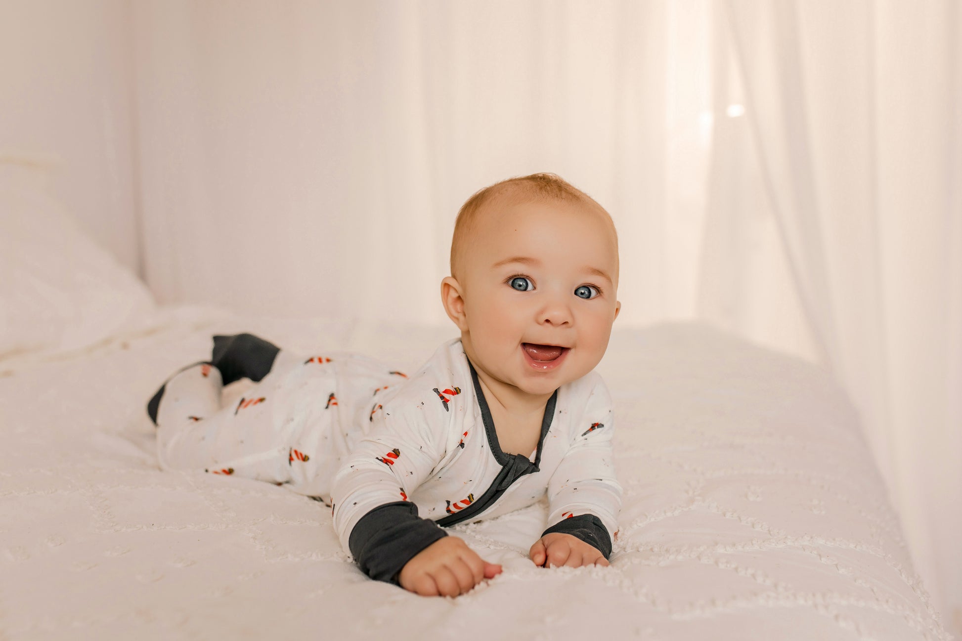 Baby wearing a white one piece with black accents and Maine lighthouses in red and white 
