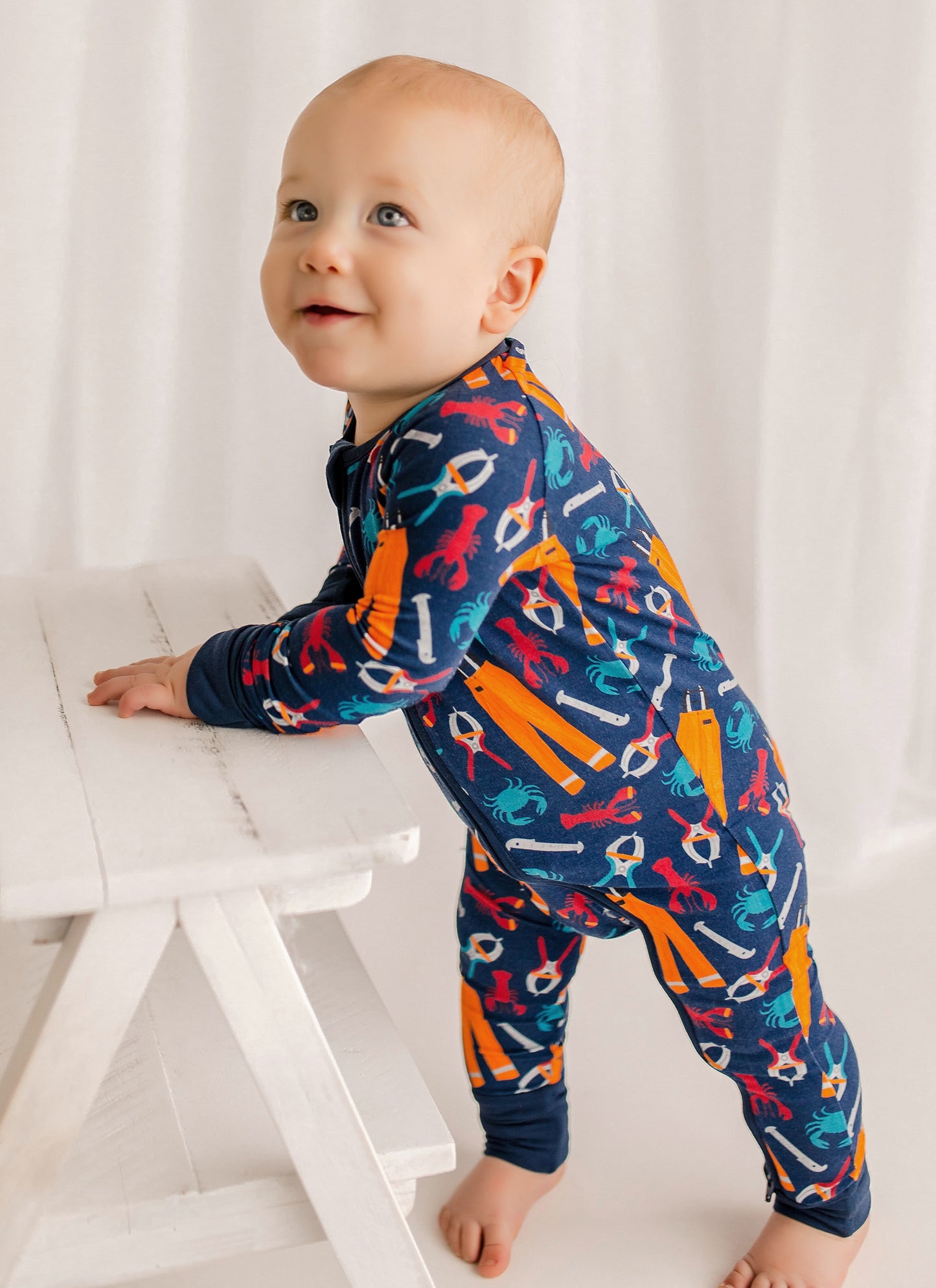 Baby wearing a colorful onesie with the tools needed work on a Maine lobster fishing boat 