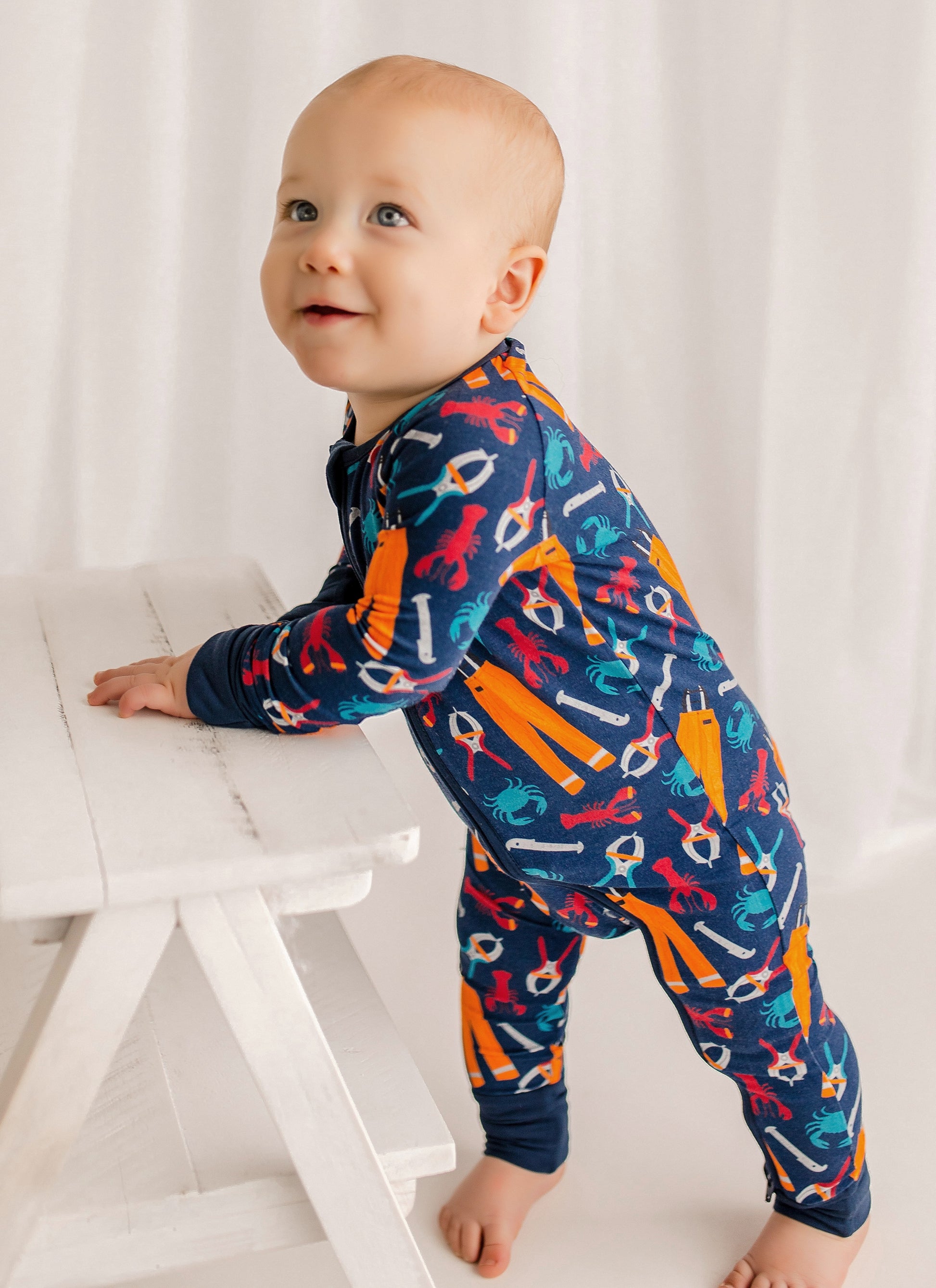 Baby wearing a colorful onesie with the tools needed work on a Maine lobster fishing boat 