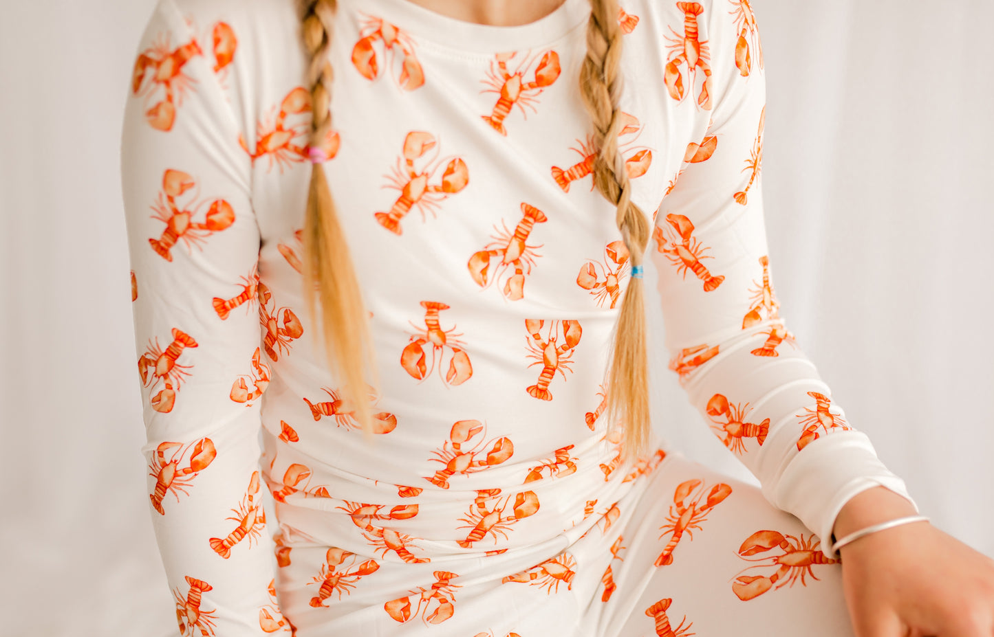 Young girl wearing a white pajamas with the Maine orange lobster patterns all over 
