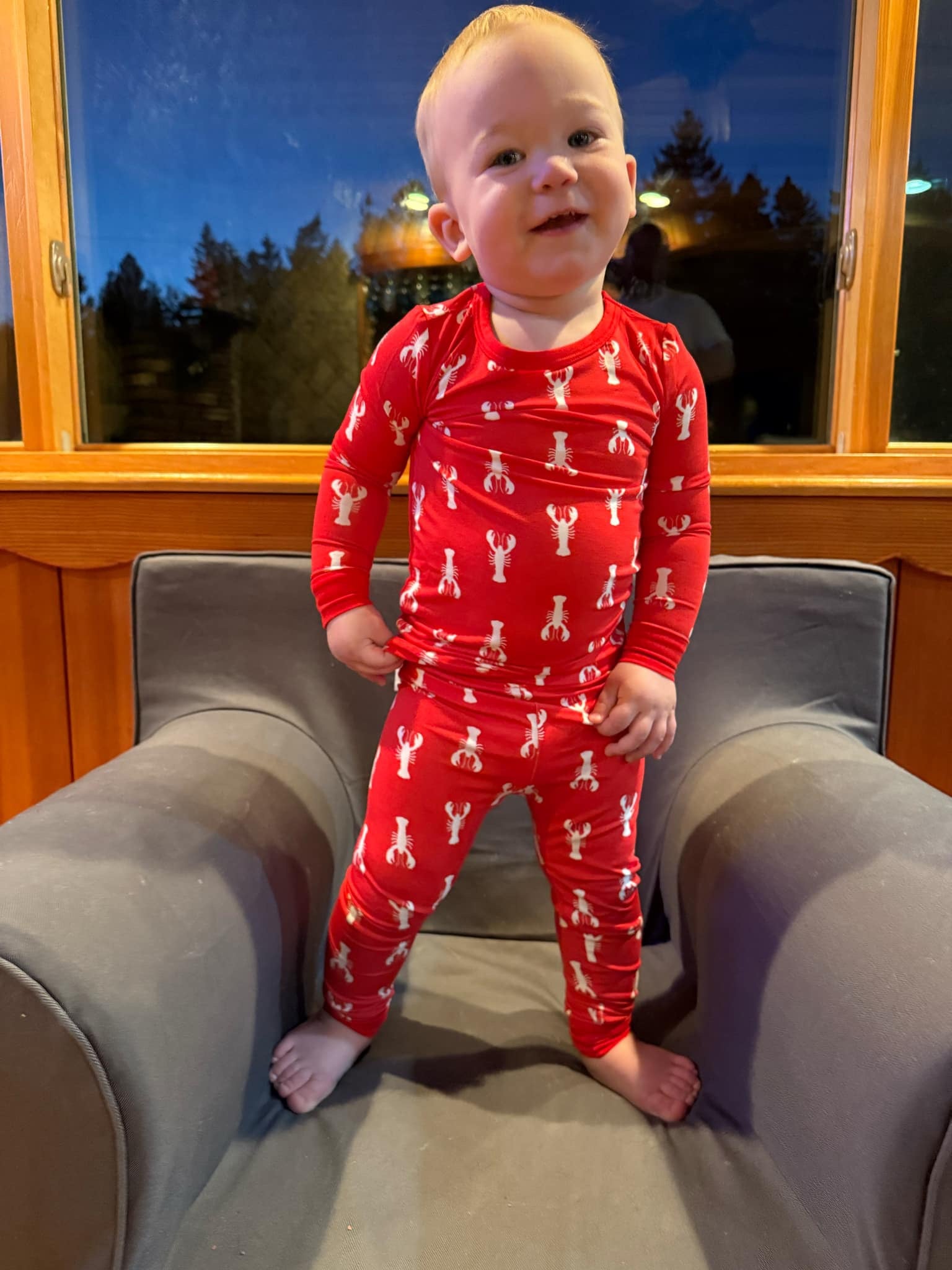 A toddler wearing red pajamas with a white lobster pattern