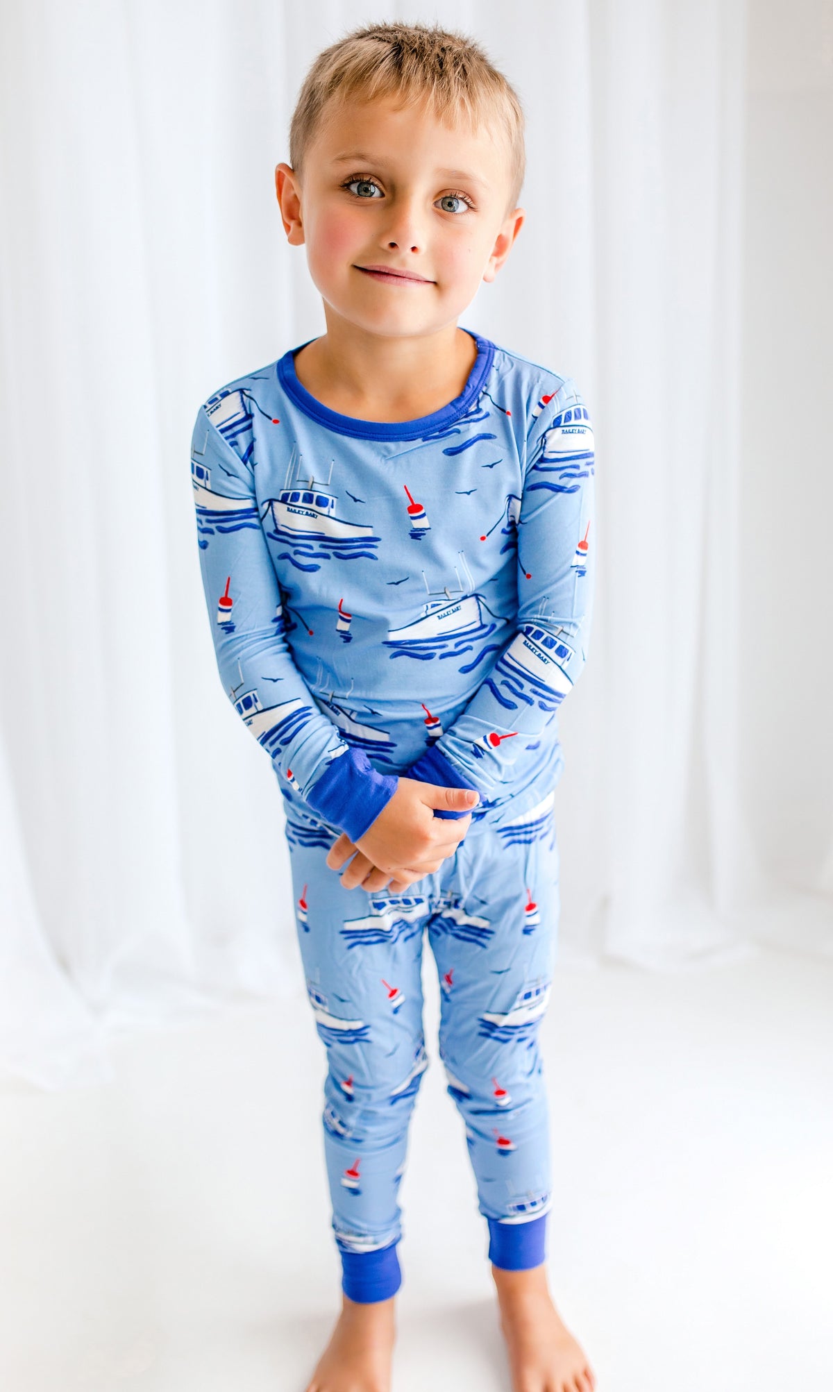 Child wearing light blue pajamas with lobster boats fishing in the Atlantic Ocean and buoys floating