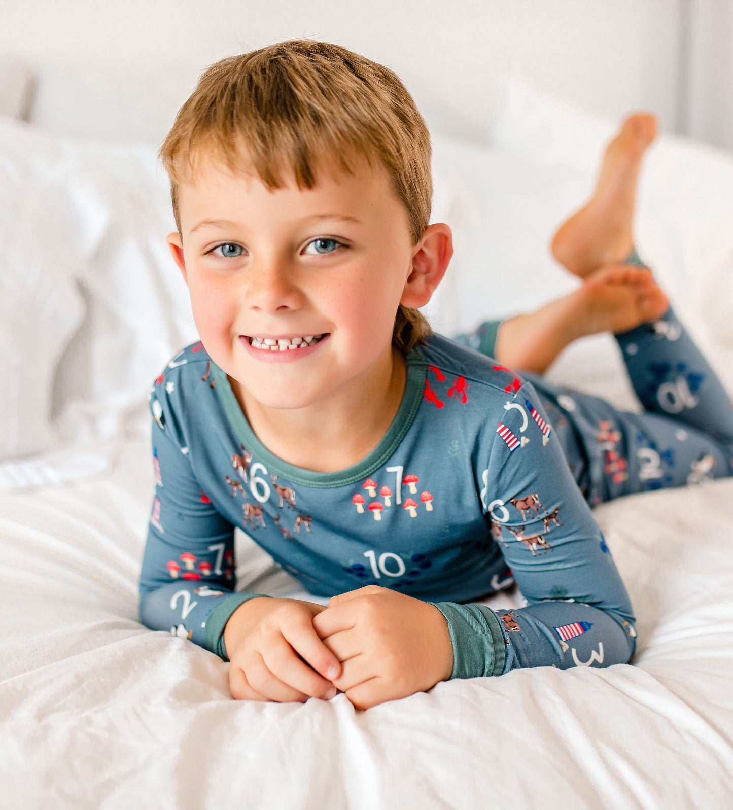 Child wearing light gray pajamas with white numbers and all different kinds of items that represent all things Maine 