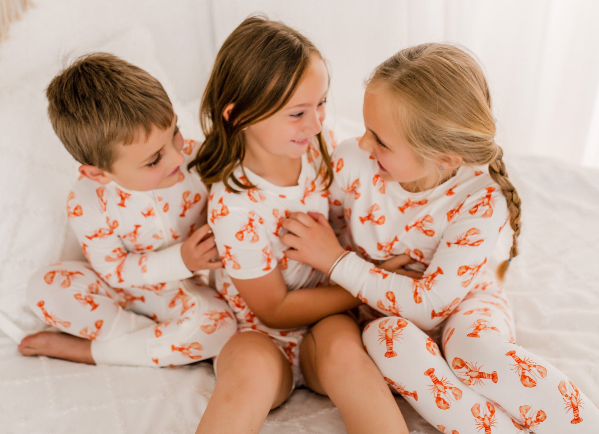 Three children in matching pajamas with orange Maine lobsters 