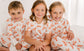 Three children wearing matching pajamas with orange lobsters caught in Maine