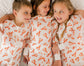 Three children wearing white pajamas with orange lobster patterns