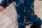 One piece pajamas set with yellow stars, yellow and white constellations, and the galaxy on a dark blue background with blue cuffs 