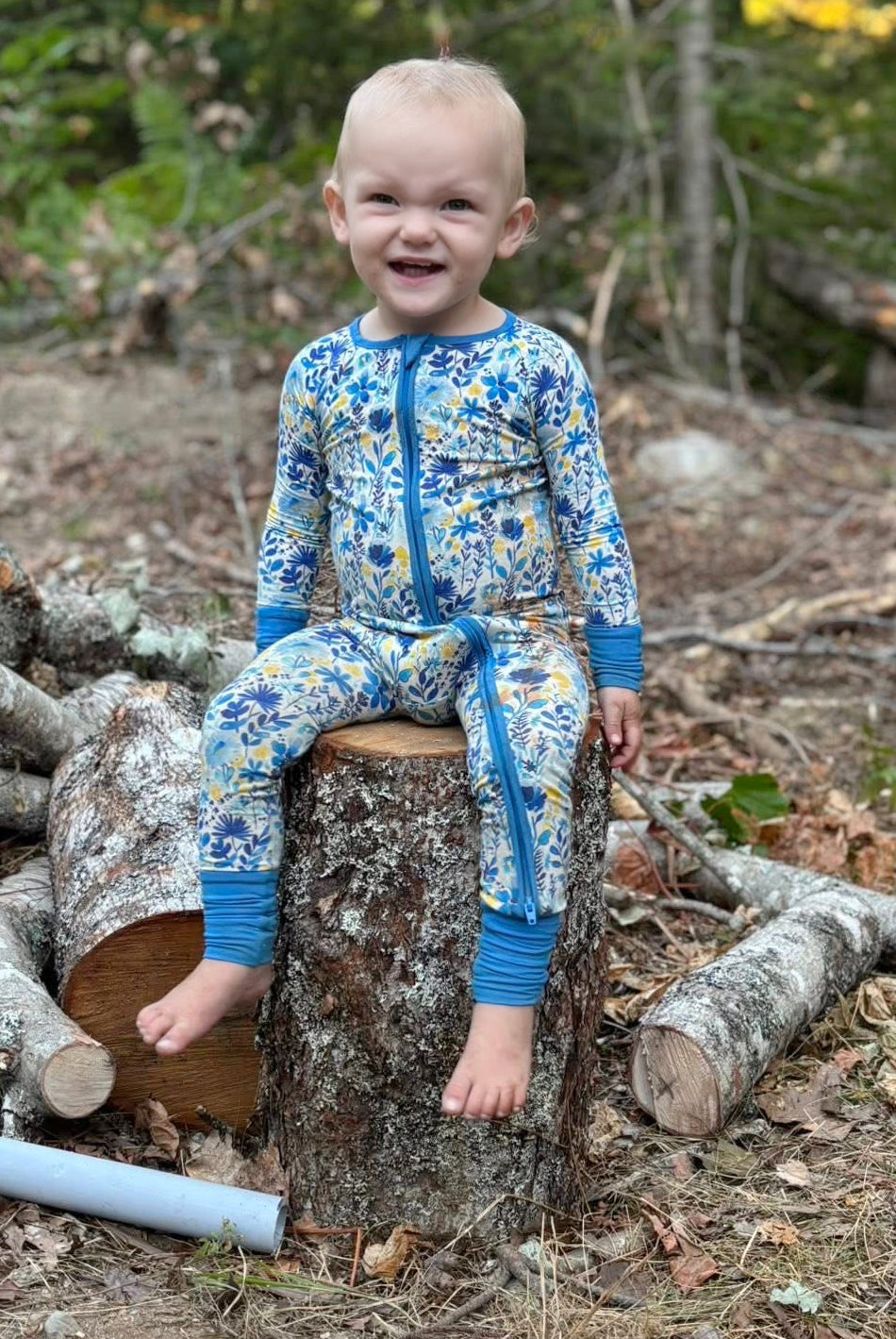 Child in a blue, yellow, and white patterned floral one piece of the Maine wildflowers 