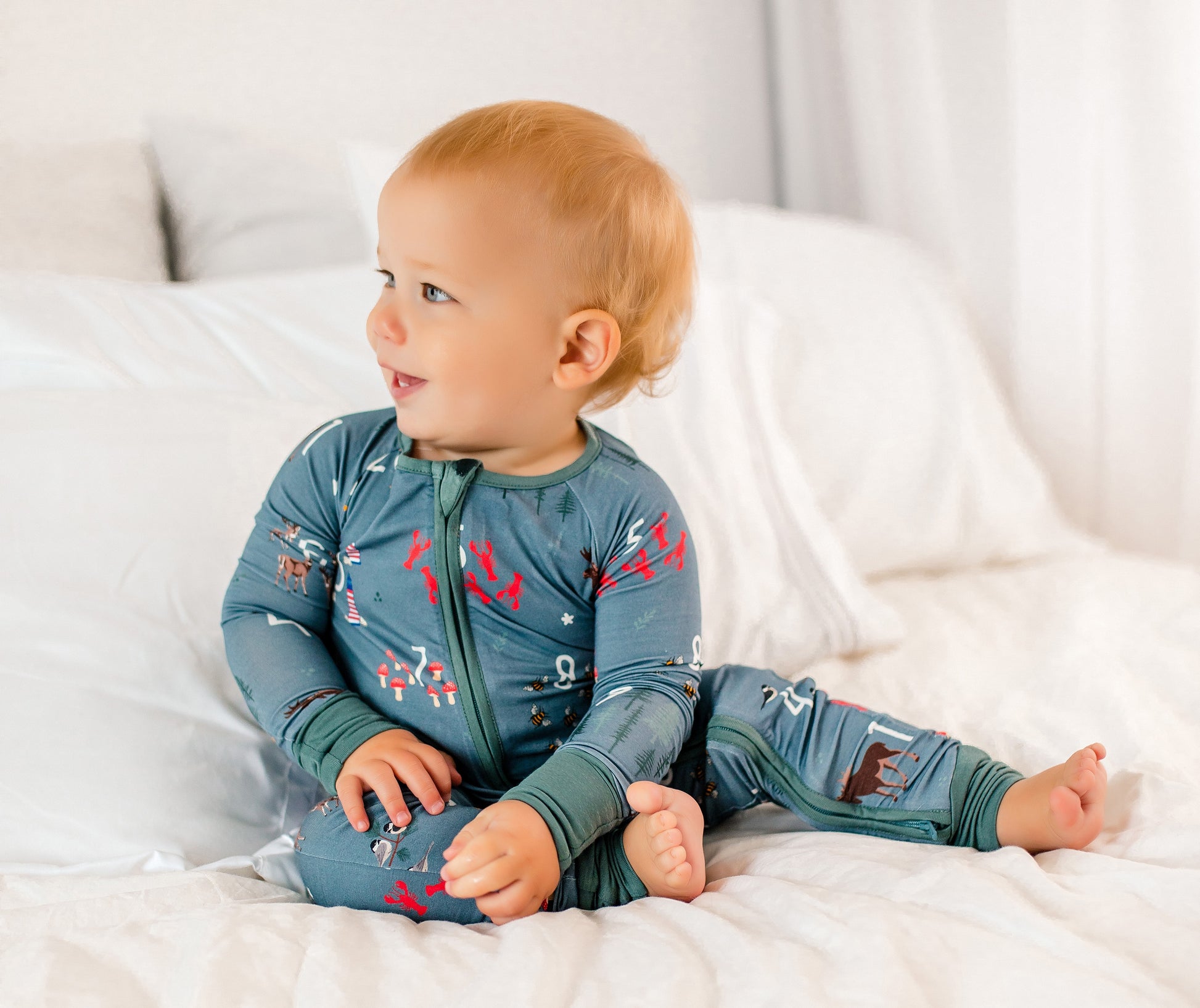 Baby wearing a light gray one piece with a bunch of items printed on it that represent all things Maine and counting numbers 1-10 